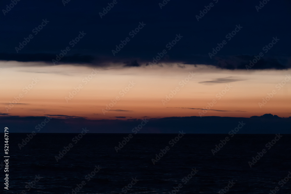Dark sunset on the sea with orange flashes of light