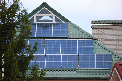 Private home roof covered with solar photovoltaic panels for generating of clean ecological electric energy in suburban rural town area. Concept of autonomous house