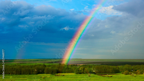 The Rainbow over a field after thunderstorm