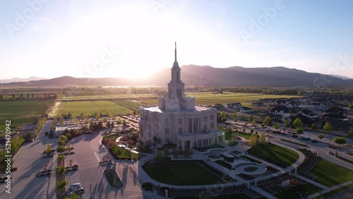 Aerial 360 degree footage of Payson Utah Temple in the middle of trees and houses under the blue sky photo