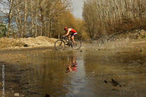 Cyclist crosses a stream with his bike and churns up the water. photo