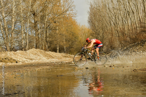 Cyclist crosses a stream with his bike and churns up the water.