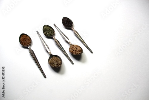 Spoons with spices ajowan, fenugreek, fennel, black and yellow mustard on white background