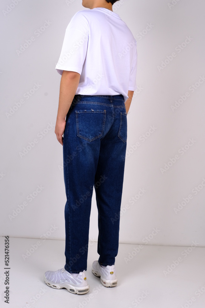 slender man in spring street clothes: skinny blue jeans and a white T-shirt. body parts: elastic male ass. concept: men's health and hemorrhoid pain. image for clothing catalog slender man in spring street clothes: skinny blue jeans and a white T-shirt. body parts: elastic male ass. concept: men's health and hemorrhoid pain. image for clothing catalog