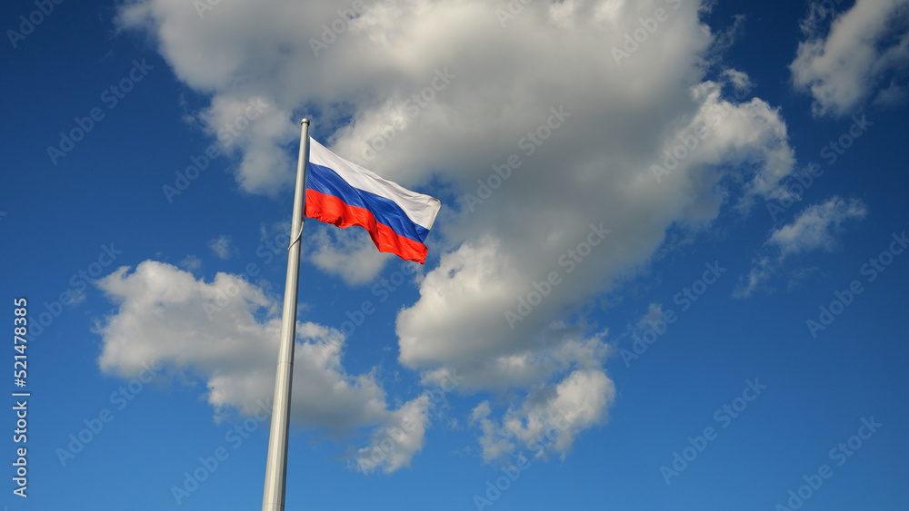 The flag of Russia develops on a flagpole in the wind in the sky
