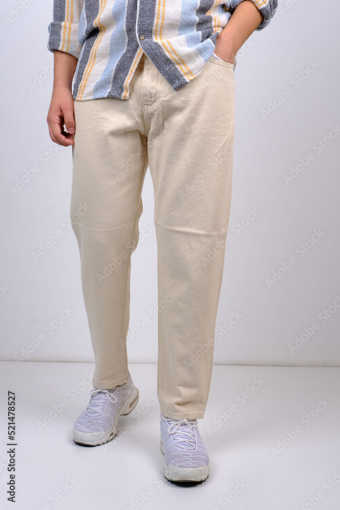 Stylish handsome confident man wearing trendy glasses, white linen shirt, pants, sneakers, posing indoors gray background. Summer fashion sense. full-length portrait Stylish handsome confident man wearing trendy glasses, white linen shirt, pants, sneakers, posing indoors gray background. Summer fashion sense. full-length portrait