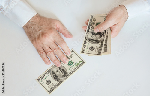 Close-up of a hand counting 100 USD bills. Male hands counting paper money. Business, finance, economy concept. Top view. photo