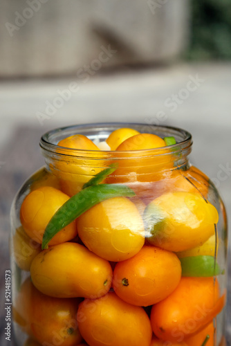 Fresh organic yellow tomatoes in a jar. Organic non-GMO yellow tomatoes on a canning table. The concept of health  non-GMO products  clean ecological food.