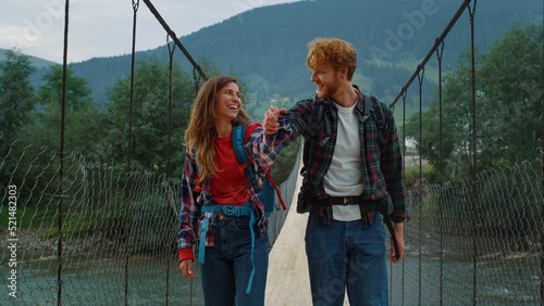 Hitchhikers walk mountains together on river bridge. Couple hold hands outside. © stockbusters