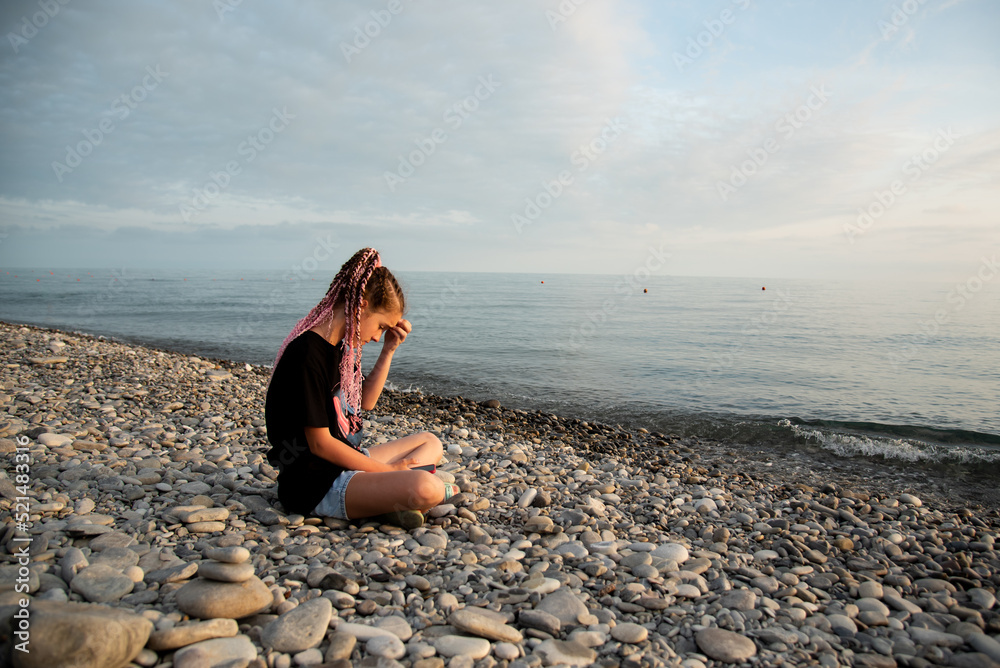 The girl sits and communicates online. Communication. Generation Z. Recreation. Sea.