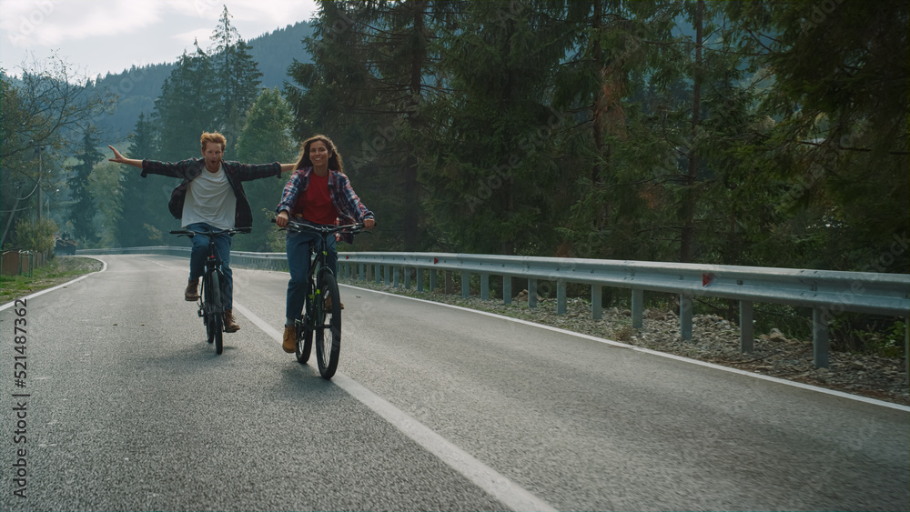 Lovers cycling mountain bikes on nature road. Happy couple enjoy sport activity.