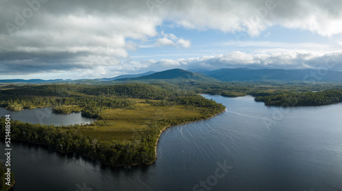 Aerial top down footage of a windy river, in the Tasmania wilderness. Lake with a Sandy beach and trees in Australia