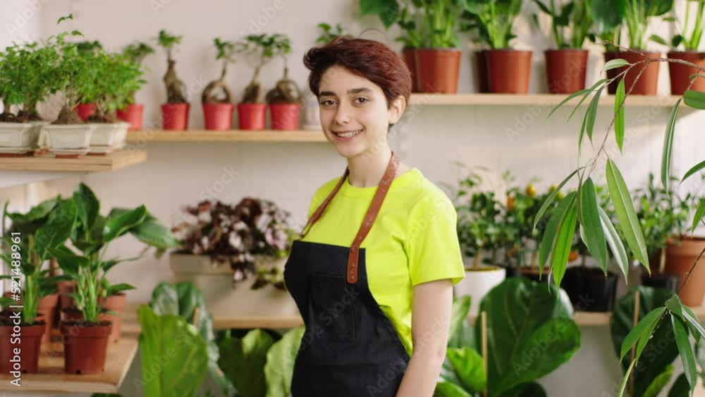 Portrait of a beautiful and pretty female florist in the floral store posing in front of the camera smiling large and feeling excited Portrait of a beautiful and pretty female florist in the floral store posing in front of the camera smiling large and feeling excited