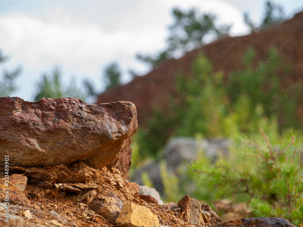 Stone in focus with mountain of slag from Falun Copper Mine World Heritage in background
