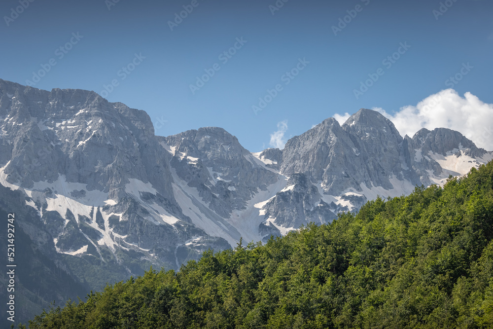 stunning high grey mountains with snow fields on a sunny day and blue sky, alpine area