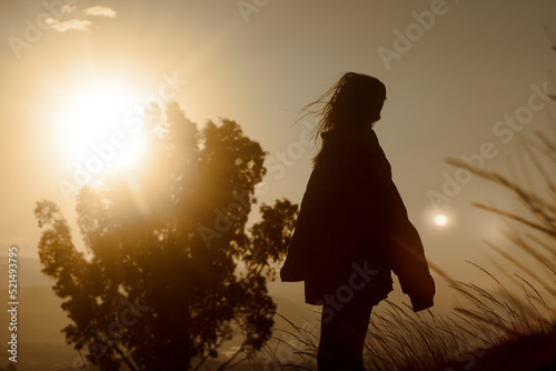 Silhouette of a young girl feeling free in sunset photo