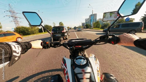 Close-up of motorcyclist s hand. Fast drone FPV. Concept of speed, breakthrough. Footage of male hands, Guy holding wheel of motorcycle. Man driving from first view at streets with cars.