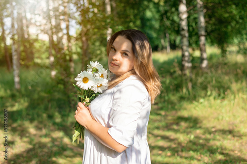 beautiful girl walks in the forest with daisies