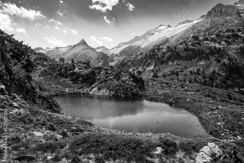 Spectacular, wonderful and evocative landscape of a lake in the Pyrenees surrounded by mountains and snow-capped peaks of Benasque. Black and white. Monochrome.