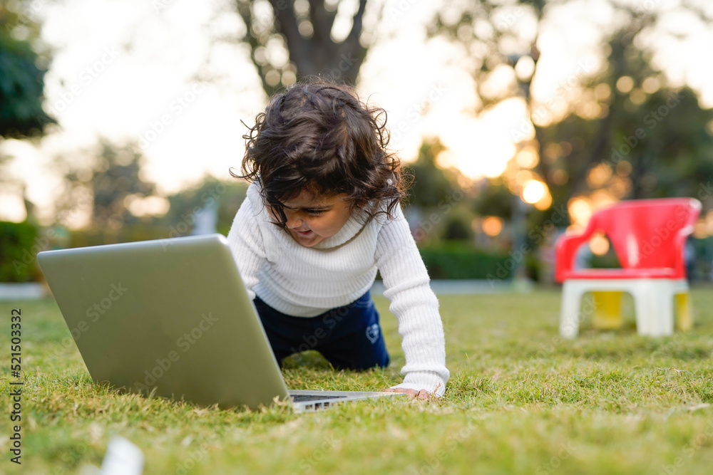 Smart little boy playing at garden while using laptop on meadow,home insurance concept. Smart little boy playing at garden while using laptop on meadow,home insurance concept.