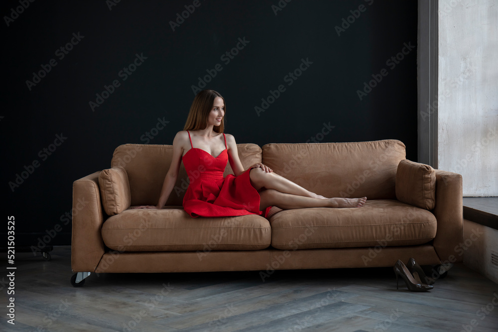young beautiful woman sitting on a sofa near the window young beautiful woman sitting on a sofa near the window