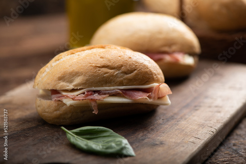 Two sandwiches with ham and cheese on wooden table