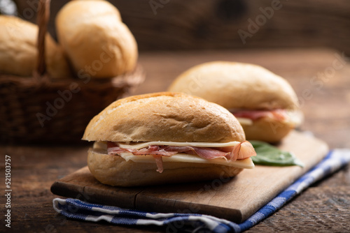 Two sandwiches with ham and cheese on wooden table