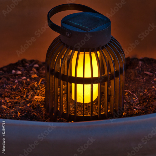 Garden Light. Isolated.Decorative solar lantern in garden pot resting on soil creating a soft moody atmosphere at night. Stock Image.