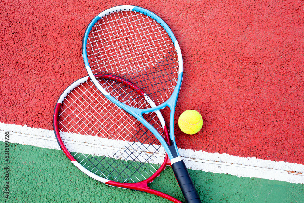 Two tennis rackets and a ball lie on the court. The theme of sports and a healthy lifestyle.