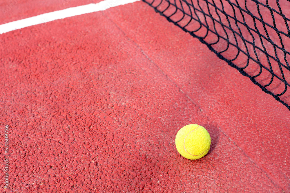 The tennis ball lies on a red tennis red court. View from the top point. Free space for text.