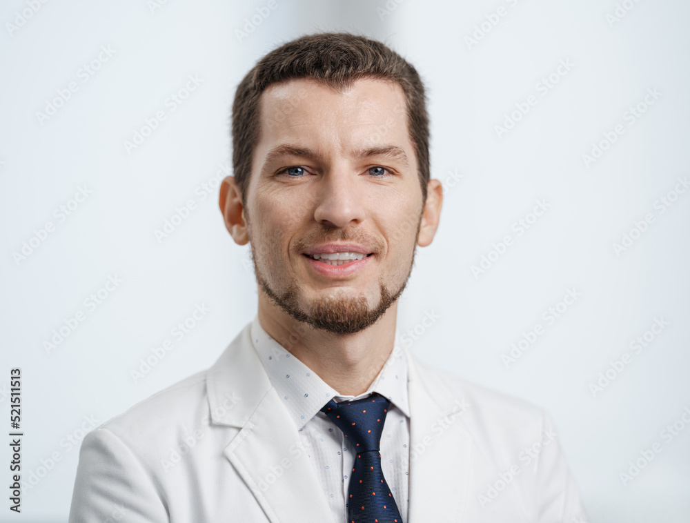 Closeup portrait of smiling male dentist in white lab coat looking at camera Closeup portrait of smiling male dentist in white lab coat looking at camera