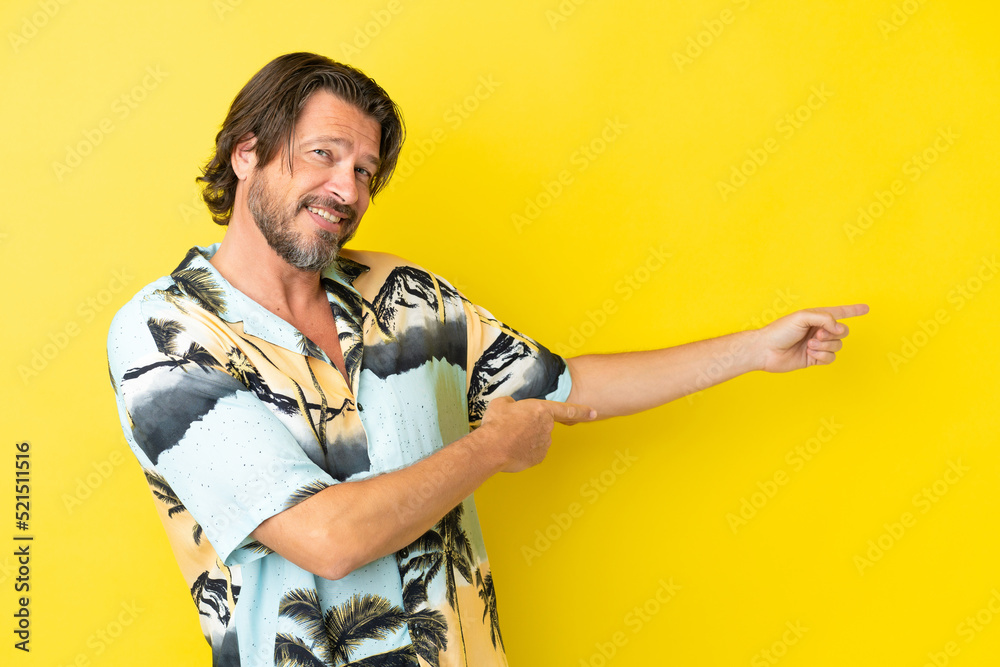 Senior dutch man isolated on yellow background pointing finger to the side and presenting a product Senior dutch man isolated on yellow background pointing finger to the side and presenting a product