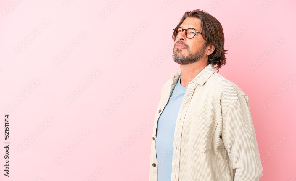 Senior dutch man isolated on pink background looking to the side