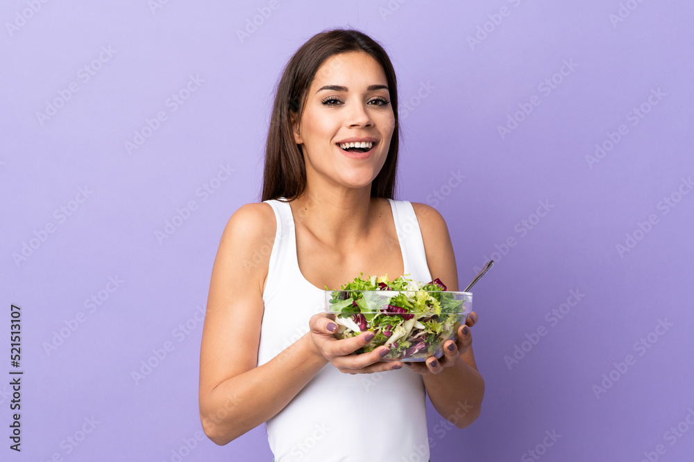 Young caucasian woman with salad isolated on purple background Young caucasian woman with salad isolated on purple background