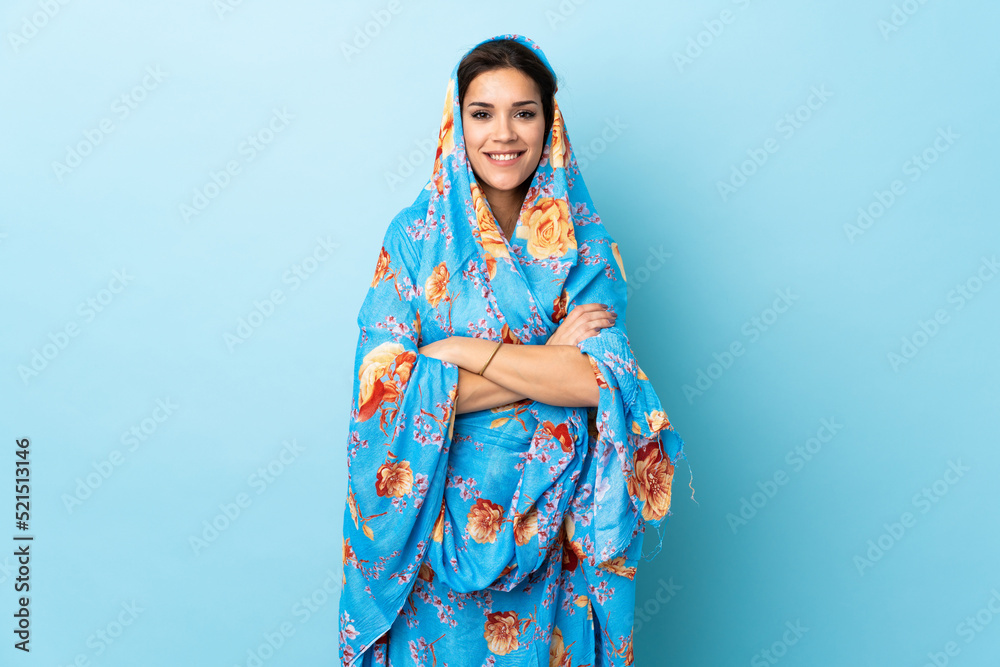 Young Moroccan woman with traditional costume isolated on blue background keeping the arms crossed in frontal position Young Moroccan woman with traditional costume isolated on blue background keeping the arms crossed in frontal position