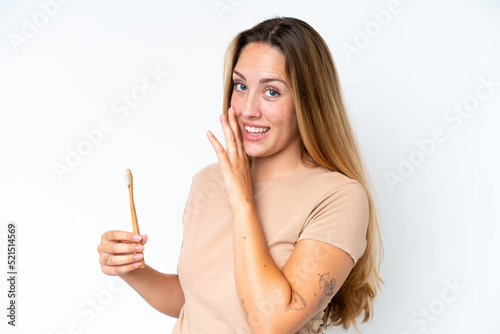 Young caucasian woman brushing teeth isolated on white background whispering something
