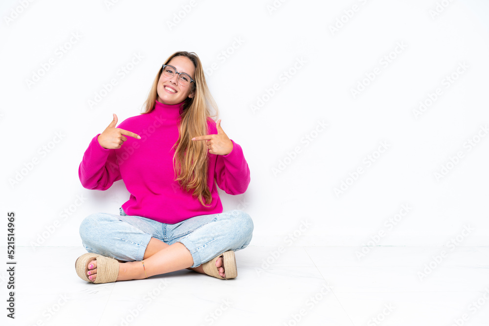 Young caucasian woman sitting on the floor isolated on white background proud and self-satisfied