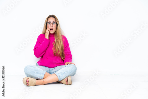 Young caucasian woman sitting on the floor isolated on white background with surprise and shocked facial expression