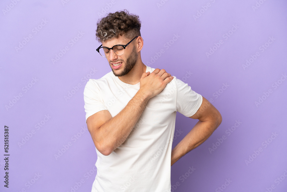 Obraz premium Delivery caucasian man isolated on purple background suffering from pain in shoulder for having made an effort