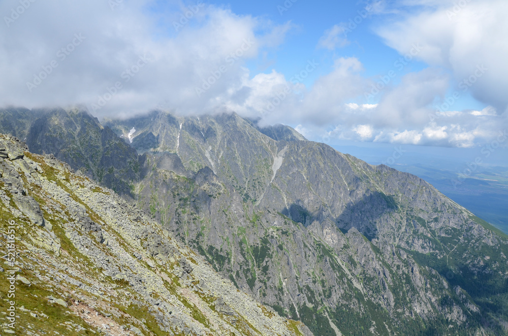 Obraz premium Amazing view of mountain rocky ridge of High Tatras mountains with blue sky and clouds on the peaks. Hiking, trekking and climbing in Slovakia.