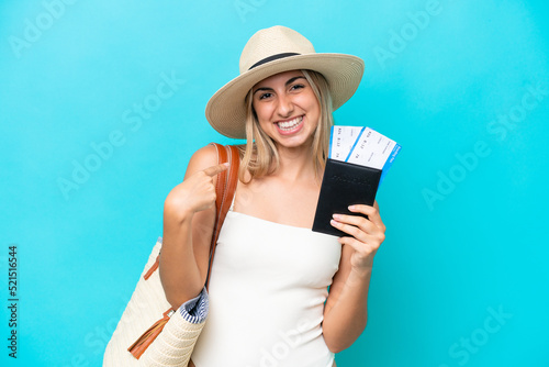 Young caucasian woman in swimsuit holding a passport isolated on blue background with surprise facial expression