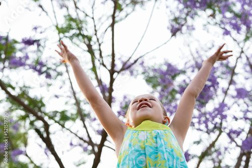 Hermosa niña levantando las manos libre feliz disfrutando del aire puro y de un hermoso día en el parque al aire libre