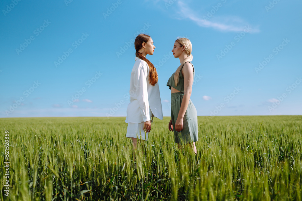 Two Beautiful posing woman in the green field. Fashion, style concept. Two Beautiful posing woman in the green field. Fashion, style concept.