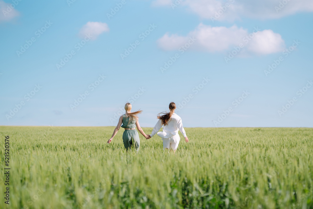 Two Beautiful posing woman in the green field. Fashion, style concept. Two Beautiful posing woman in the green field. Fashion, style concept.