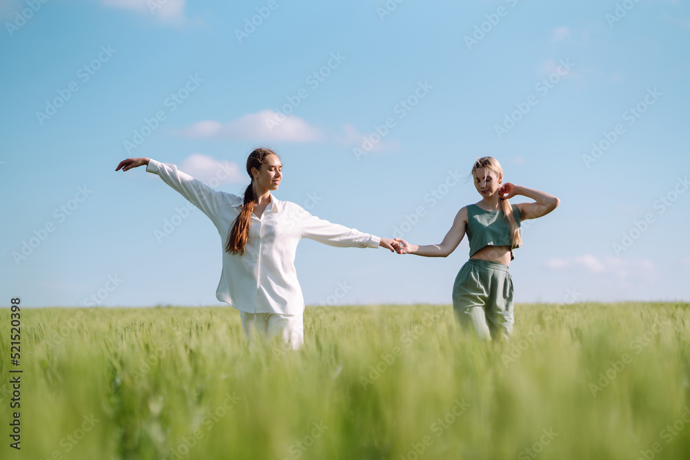 Two Beautiful posing  woman in the green field.  Fashion, style concept.