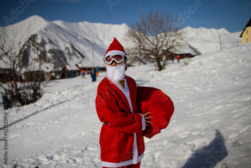 Man in Santa Claus hat with a snowboard at a ski resort.