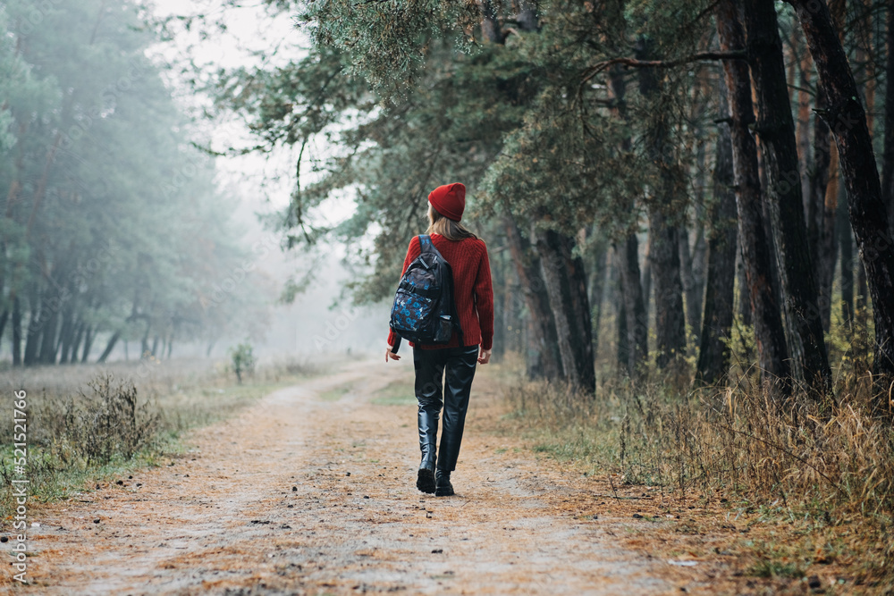 Weekend breaks and getaways in forests. Stay close to nature. Young woman in red hat and sweater with backpack Weekend breaks and getaways in forests. Stay close to nature. Young woman in red hat and sweater with backpack