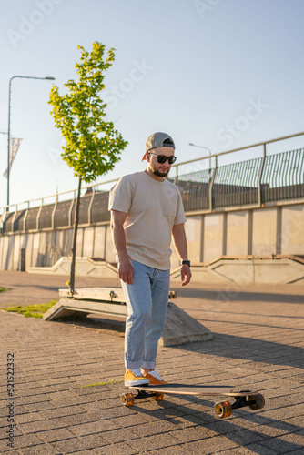 handsome young hipster guy spending free time on active skateboard hobby vacations outdoors. © Julija