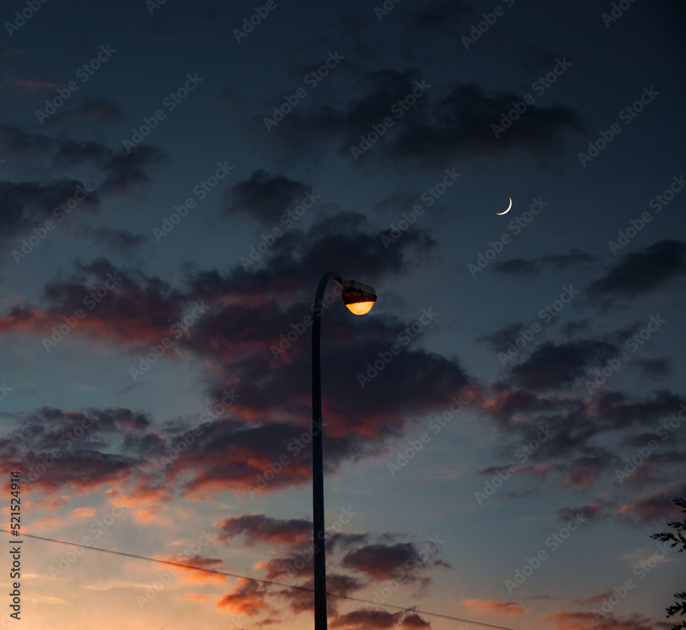 Crescent moon at sunset with a streetlamp