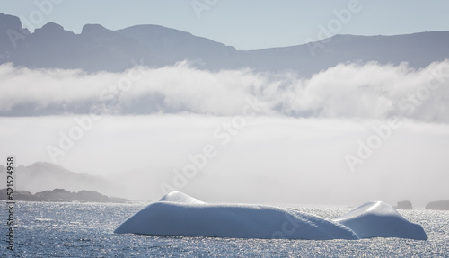 Iceberg in Prince Christian Sound with mountains and low hanging cloud in background in South Greenland